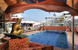 Costa Magica - Costa Cruises - bronzová nymfa a bazén na horní palubě za bílého slunečního dne